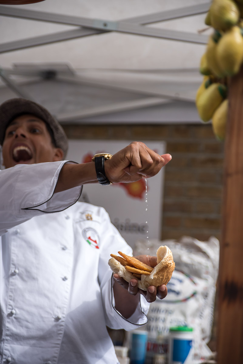 Chef squeezes fresh lemon over a sandwich in a street food market in Sicily