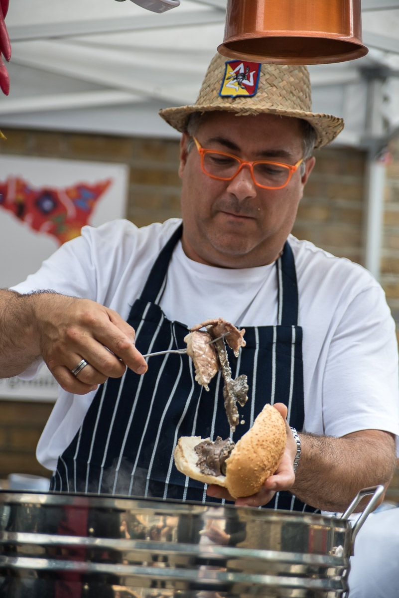 Chef prepares a traditional meat sandwich Pane con la Milza in a street food market in Sicily