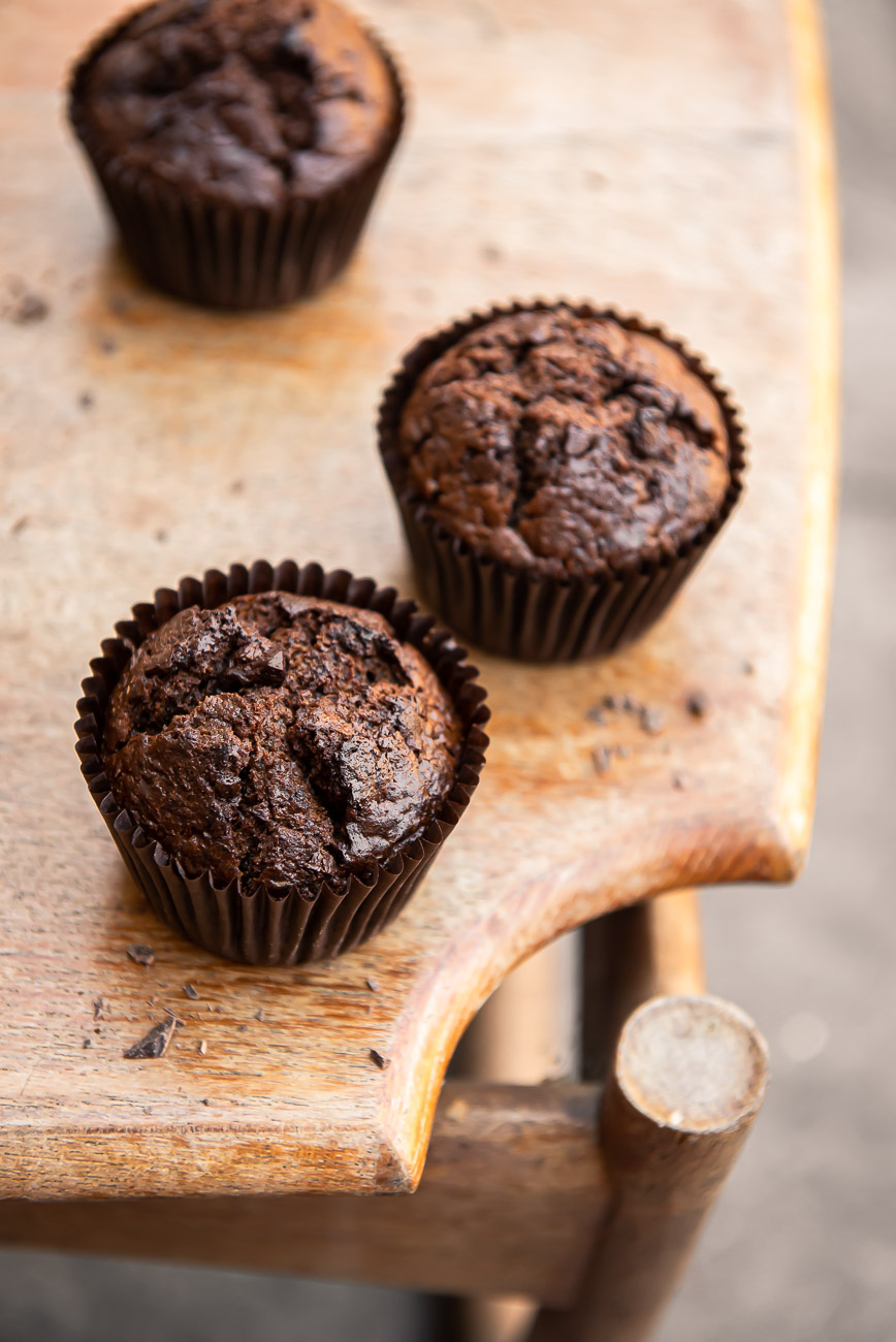 Three chocolate muffins on a light wooden table no garnish