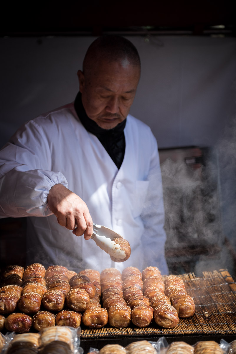 man prepares street food in Tsukiji market in Tokyo