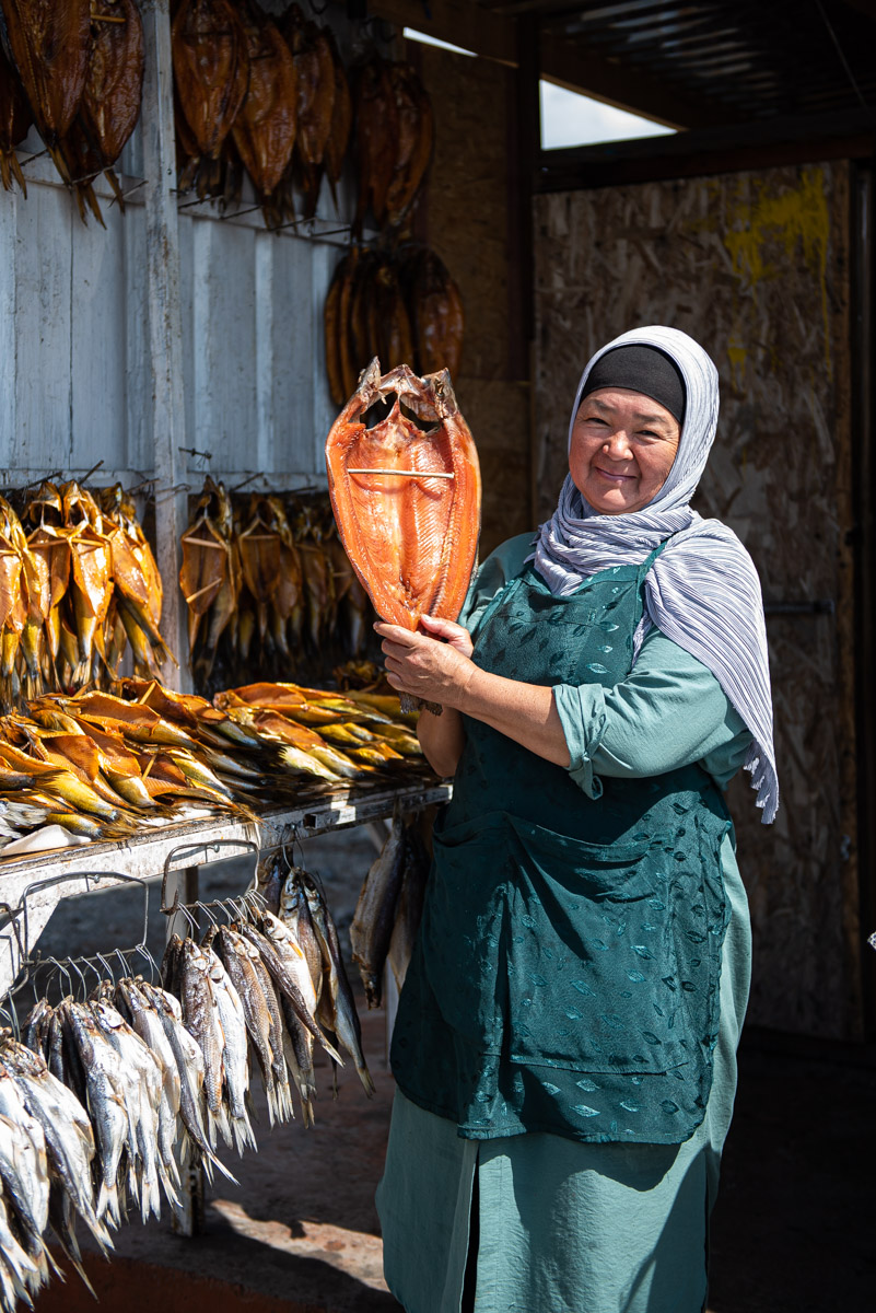 tips for street food photography - vendor in Kyrgyzstan showcasing her smoked fish